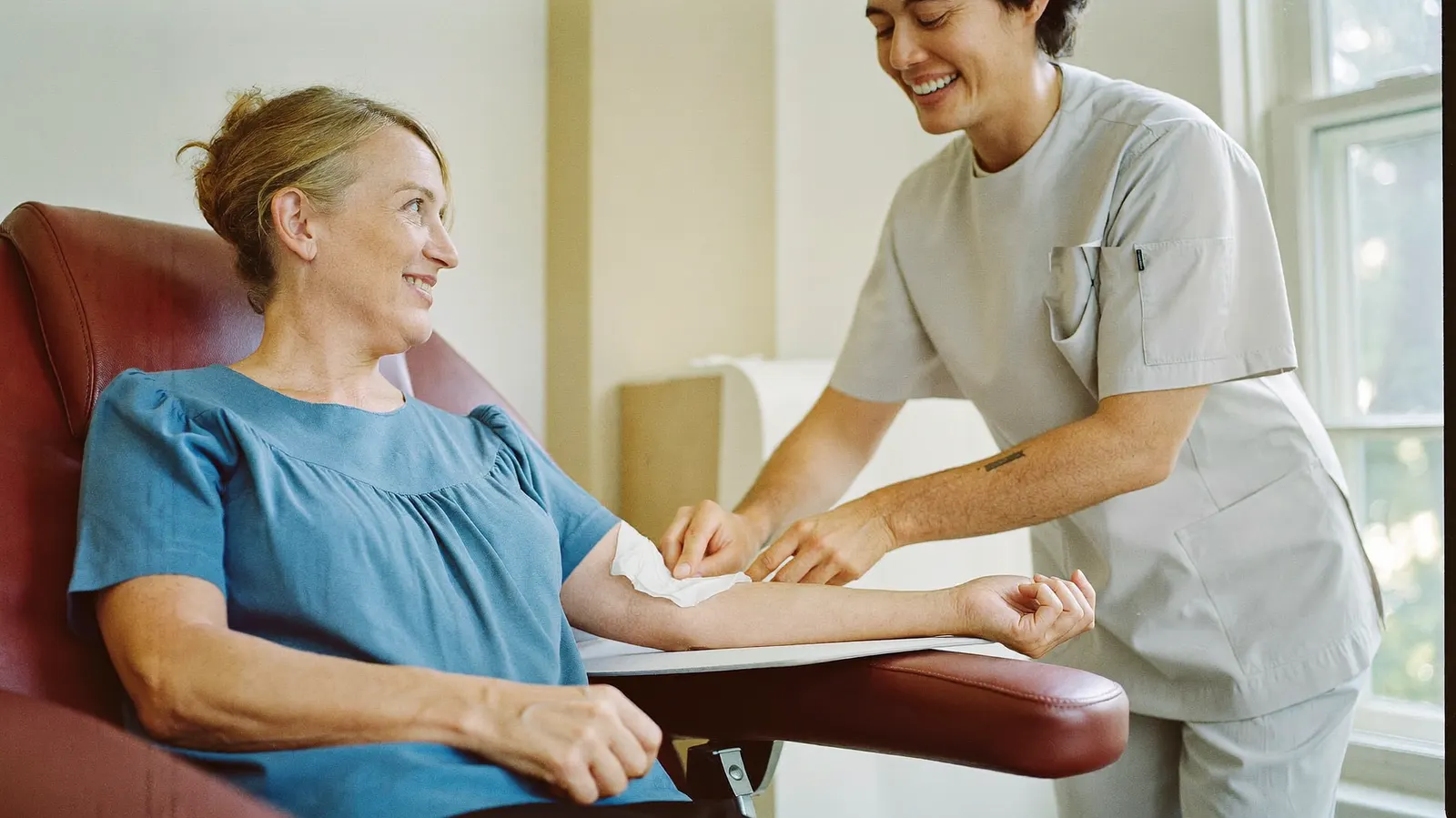 Phlebotomist sharing a smile with a patient after a routine blood draw in a bright draw room.